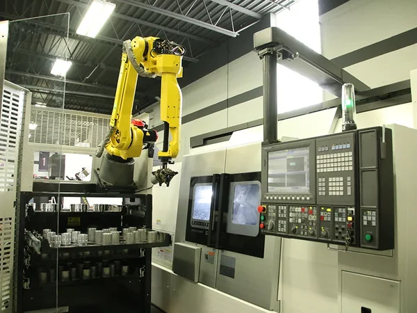 robot arm tending CNC machine in smart factory for automated part loading